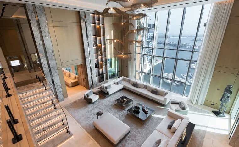 A double-height luxury living room with floor-to-ceiling windows over the water