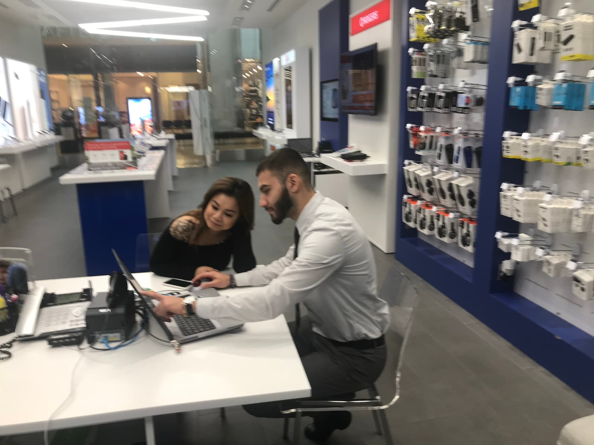 A young Navid Rashid helping a customer on a laptop inside a Glentel store