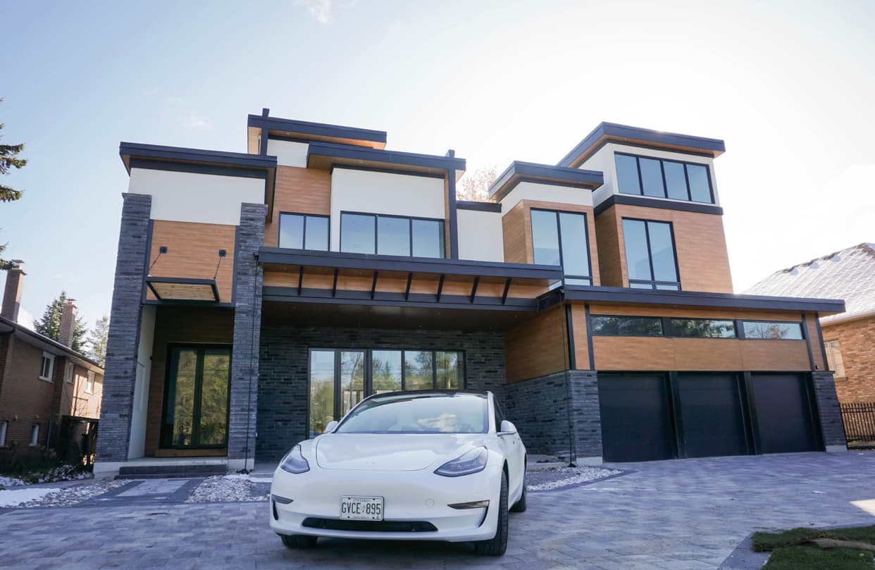A modern luxury home in Toronto with a white Tesla parked out front