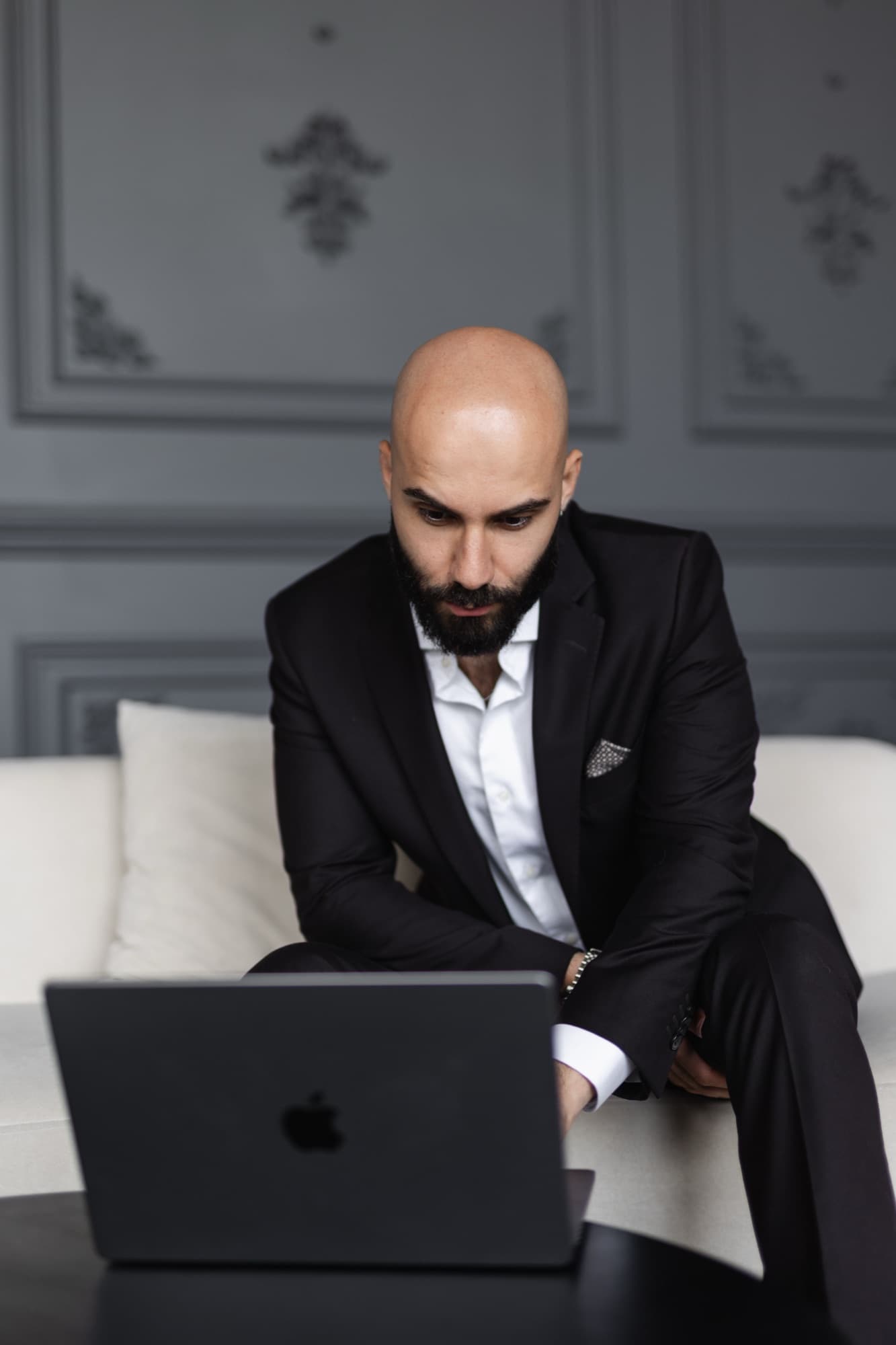 Navid Rashid working on a laptop on a cream sofa